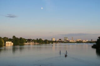 Hotel Atlantic Ruhiger Fluss mit Stadtansicht, Sportler auf dem Wasser und Vollmond im Hintergrund.