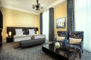 Elegant hotel room with two beds, stylish armchairs and modern furnishings.