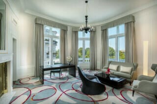 Elegantes Wohnzimmer mit großen Fenstern, stilvollem Mobiliar und moderner Dekoration.