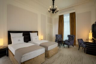 Helles Hotelzimmer mit zwei Betten, eleganten Stühlen und modernem Interieur.
