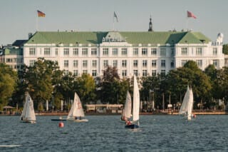 Blick auf das Hotel Atlantic mit Segelbooten auf dem Wasser im Hintergrund.