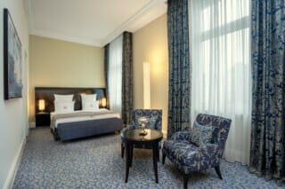 Elegant hotel room with double bed, stylish furniture and large windows.