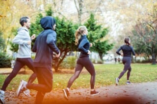 Hotel Atlantic Läufer in sportlicher Kleidung joggen durch einen herbstlichen Park mit buntem Laub.