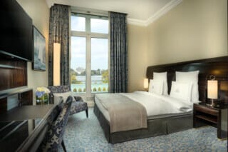 Elegant hotel room with a view of the lake, stylish decor and modern amenities.