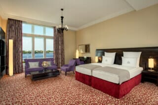 Elegantes Hotelzimmer mit Blick auf das Wasser, gemütlichem Mobiliar und stilvollem Dekor.
