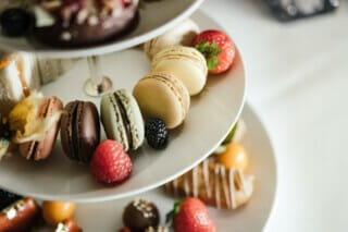 Bunte Macarons und frische Früchte auf einer eleganten Etagere für einen stilvollen Genuss.