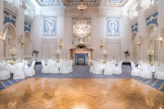 Eleganter Veranstaltungsraum mit Kerzen, weißen Tischdecken und opulenter Dekoration.