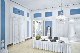 Eleganter Innenraum mit blauen Wänden, Kronleuchter und dekorativem Tisch für Veranstaltungen.