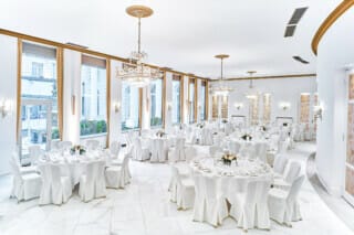 Eleganter Veranstaltungsraum mit runden Tischen und Kristallleuchtern in heller Atmosphäre.