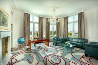 Elegantes Wohnzimmer mit Panoramafenstern, modernen Möbeln und stilvollem Teppichdesign.