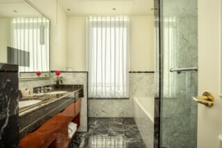 Elegantes Badezimmer mit Marmoroberflächen, Doppelwaschbecken und natürlichem Licht.