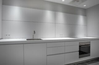 Moderne, minimalistische Küche mit Edelstahlspüle und Kochfeld in neutralen Farben.