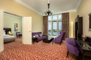 Elegantes Hotelzimmer mit lila Möbeln, Blick auf den Fluss und modernem Dekor.