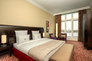 Elegant hotel room with double bed, seating area and view of the river. Cosy atmosphere.