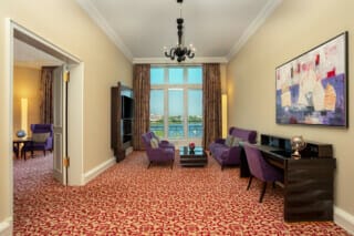 Elegant living room with purple furniture, large window and view of the countryside.