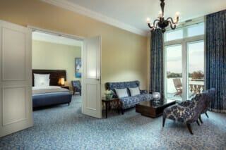 Luxuriöses Hotelzimmer mit Balkon, eleganter Einrichtung und gemütlichem Sitzbereich.