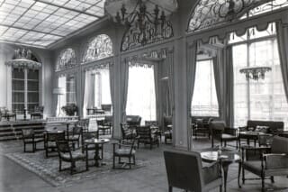 Eleganter Lounge mit historischen Möbeln, großen Fenstern und kunstvollen Verzierungen.
