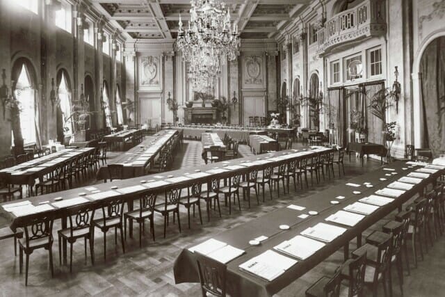 Eleganter Saal mit langen Tischen, Kerzenleuchtern und historischen Details im Hintergrund.