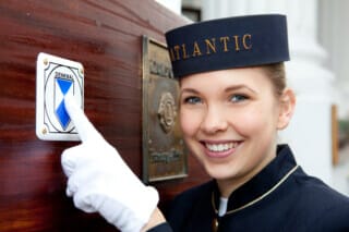 Mitarbeiterin des Atlantic Hotels zeigt auf das Denkmalschild mit einem Lächeln.