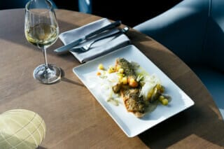 Gegrillter Fisch mit Gemüsebeilage und Weißwein auf einem eleganten Tisch serviert.