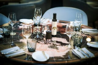 Elegant gedeckter Tisch mit Olivenöl, Gläsern und Kerze in modernem Restaurant.