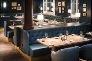 Hotel Atlantic Elegantes Restaurantinterieur mit blauen Polsterbänken und stilvollen Holztischen.