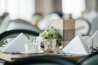 Hotel Atlantic Elegant gedeckter Tisch mit Servietten, Gläsern und Blumenarrangement in Restaurant.