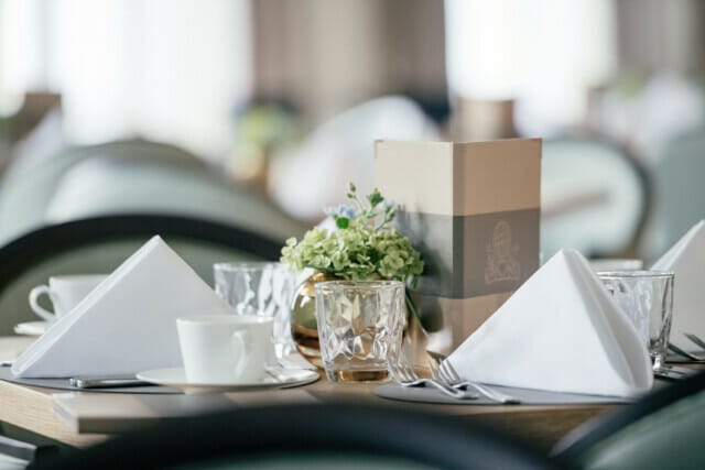 Elegant gedeckter Tisch mit Servietten, Gläsern und Blumenarrangement in Restaurant.