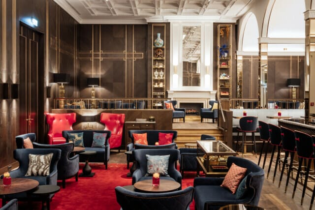 Elegante Lounge mit roten und blauen Sesseln, Holzdekor und stilvollem Ambiente.