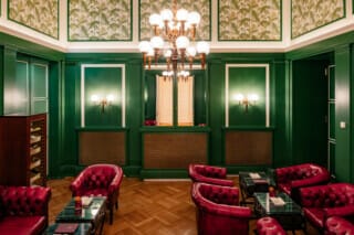 Hotel Atlantic Eleganter Salon mit grünen Wänden, roten Ledersesseln und stilvoller Beleuchtung.