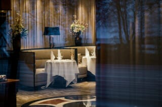 Elegantes Restaurant mit gedeckten Tischen, stilvollen Blumen und gedämpfter Beleuchtung.