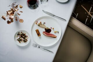 Gourmetgericht mit Entenbrust, Beilagen und Rotwein auf elegantem Tisch gedeckt.