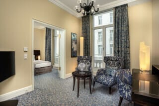 Elegant hotel room with blue curtains, stylish armchairs and modern furnishings.