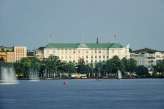 Hotel Atlantic am Wasser mit grüner Dachlandschaft und umgebenden Bäumen in Hamburg.