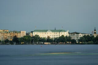 Blick auf das Hotel Atlantic und die umliegenden Gebäude am Wasser in Hamburg.