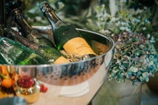 Bottle of sparkling wine in an ice bucket, surrounded by fresh flowers and decorative elements.