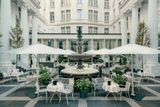 Eleganter Innenhof mit Brunnen, Tischen und Sonnenschirmen in einem stilvollen Restaurant.