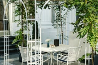 Eleganter Außenbereich mit Tisch, Stühlen und Pflanzen unter einem weißen Pergola.