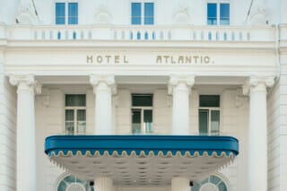 Fassade des Hotel Atlantic mit Säulen und blauem Vordach, eleganter architektonischer Stil.