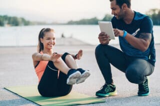Hotel Atlantic Sportswoman making sit-ups outdoors with the help of a trainer