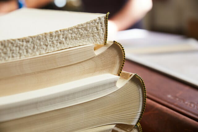 Drei gestapelte Bücher mit detailliertem Buchschnitt und handwerklicher Bindung.