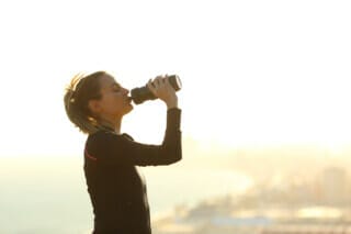Hotel Atlantic Frau trinkt Wasser aus einer Flasche bei Sonnenuntergang am Strand.