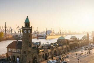 View of Hamburg harbour with historic buildings and cranes in the sunlight.