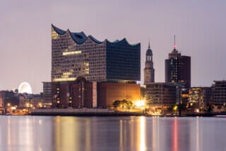 Hotel Atlantic Elbphilharmonie Hamburg with a view of the harbour at night, illuminated by city lights.