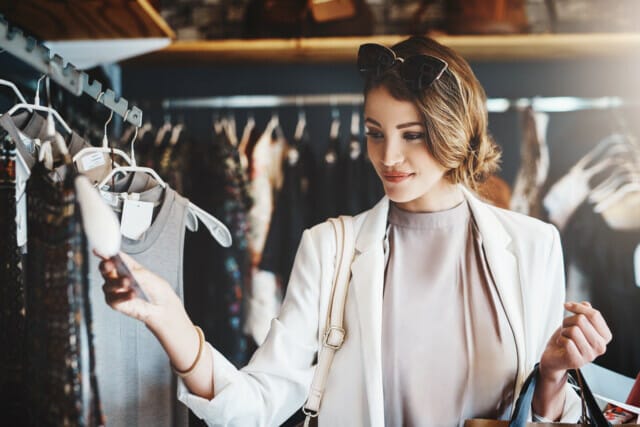 Frau in eleganter Kleidung beim Einkaufen in einem Modegeschäft, schaut sich Kleidung an.