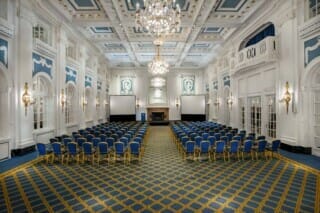 Eleganter Konferenzraum mit blauen Stühlen und luxuriösem Chandelier-Design.