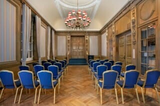 Eleganter Besprechungsraum mit blauen Stühlen und stilvollem Kronleuchter.