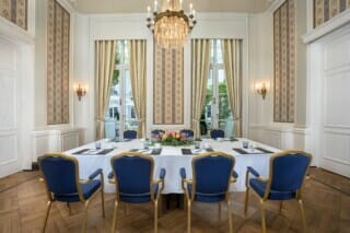 Eleganter Konferenzraum mit blauen Stühlen, Tischdekoration und viel natürlichem Licht.