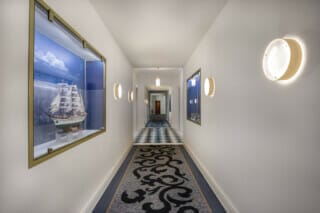 Eleganter Flur mit Schiffsmodell und stilvoller Beleuchtung in einem modernen Hotel.