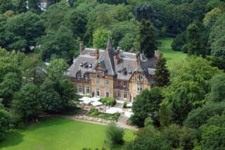 Historisches Schloss umgeben von üppigem Grün und gepflegten Gärten in der Natur.